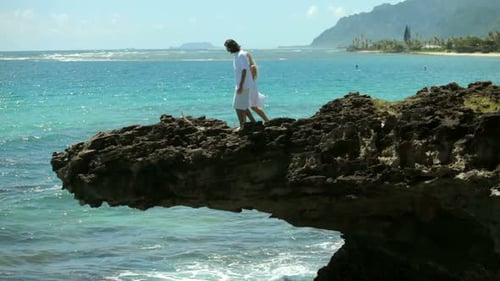 Couple Stand On Rocks Overlooking Ocean