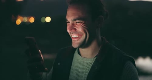 Smiling Man Using Phone Outside at Night