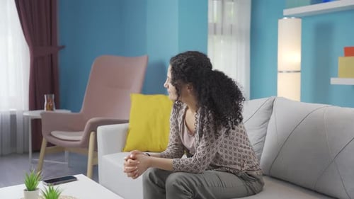 Pensive Woman Sitting on Couch Indoors During Daytime