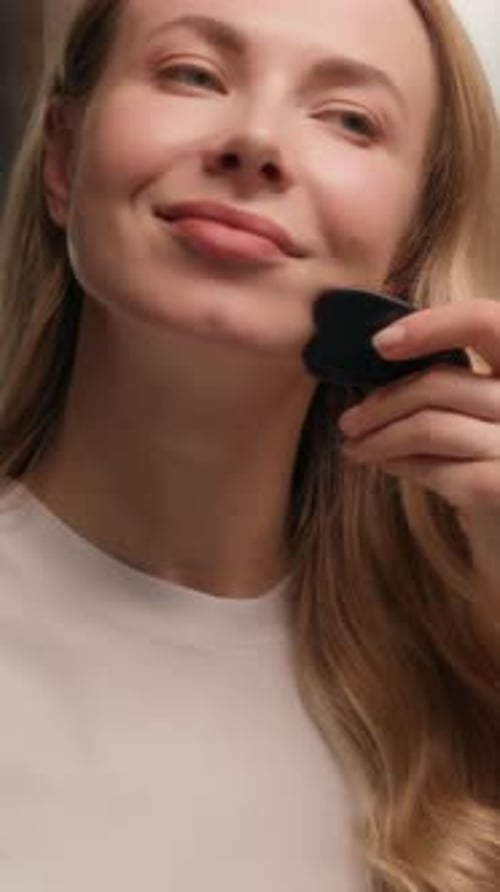 Woman Massaging Face with Gua Sha Beauty Tool
