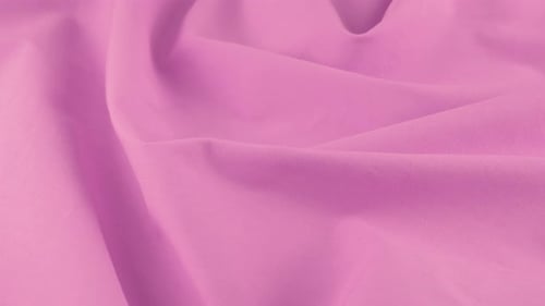 Top view of the soft folds of the medium orchid cotton fabric. The textile background rotates