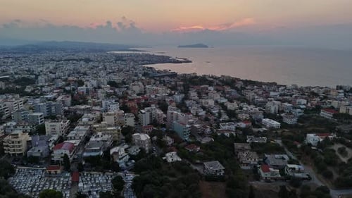 Aerial view of a coastal city at sunset with distant islands