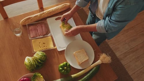 Close-up of hands of young man cooking sandwich standing in the kitchen