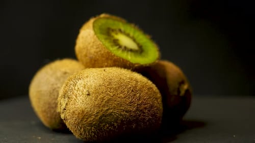 Kiwifruit, kiwi, rotating sliced fruit, black background. Selective focus. Static shot. Scene D.