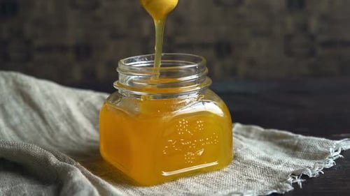 Honey Dripping in Bottle. Honey Flowing From Dripper. Honey Pouring in Jar