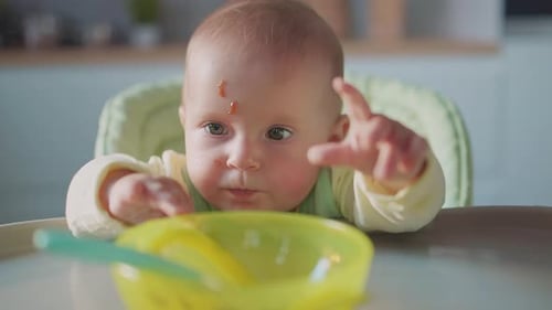Cute Infant Eating Food in High Chair