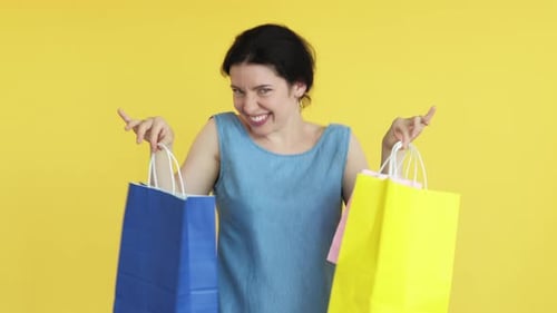 Woman Holding Shopping Bags on Yellow Background