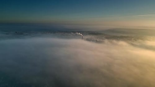 Aerial Drone scene above the Urban townscape area shrouded In thick morning mist. Warm morning sunli
