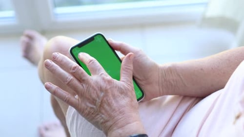 Senior Mature Woman Hands Holding Smartphone with Green Mockup Screen