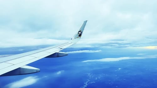 Asa de um avião voando acima das nuvens no céu azul. Vista de uma janela do avião. Conceito de