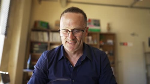Adult Man in Glasses Sits in Front of a Laptop and Types
