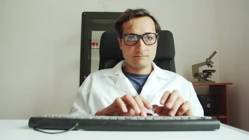 Man Typing Data into Computer at Desk