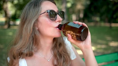 Femme buvant de la limonade au kombucha dans un parc arboré, Ralenti