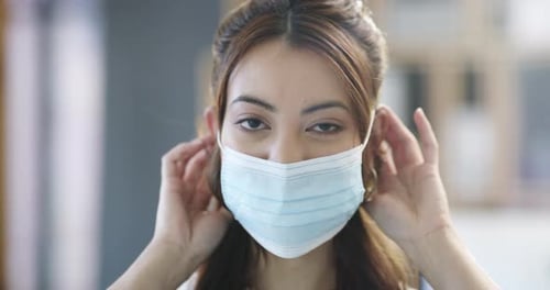 4k video footage of a businesswoman putting her mask on at the office