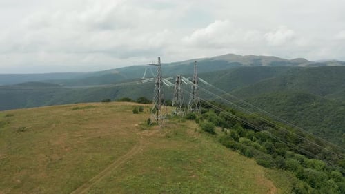 Aerial view of transmission towers in georgian mountains. Green hazed hills in the background. 4k fo