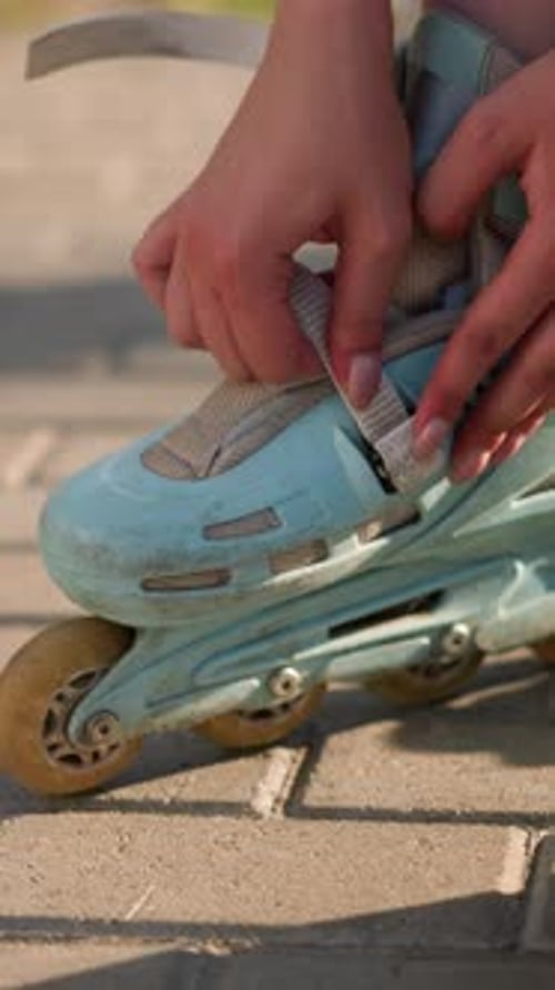 CloseUp of Individual Adjusting Strap on Roller Skate Under Sunlight with Sneakers