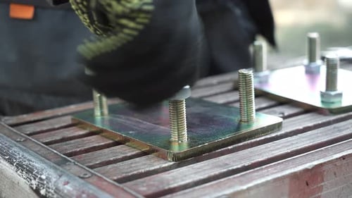 Gloved Hand Fastening Nut Onto Bolt