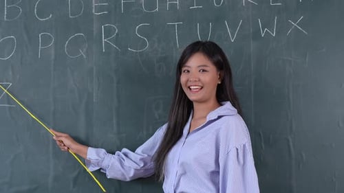 Teacher Points to Alphabet on Chalkboard