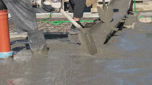 Beton gießen Bauarbeiter bauen Fundament verteilen nassen Zement mit Schaufeln auf einem