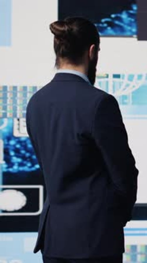 Man Explains Financial Data on Multiple Screens