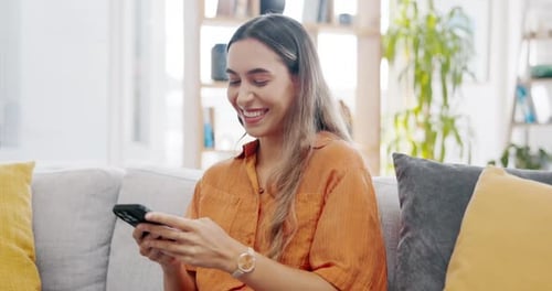 Smiling Woman Using Phone on Sofa at Home