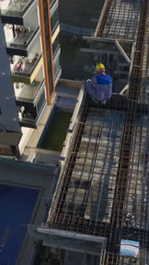 Vertical Video of Workers Pouring Concrete While a Crane Moves Heavy Materials on a Residential Site