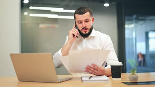 Angry and Stressed Businessman Shouting on Phone Call with Documents in Office