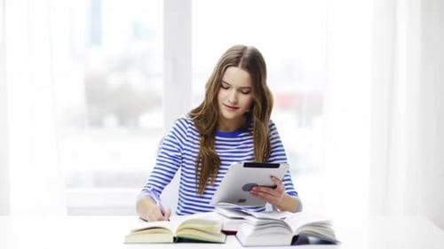 Smiling student girl at home with tablet computer studying for university