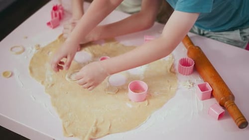 Kinder schneiden und arrangieren Teigformen während der Backaktivität