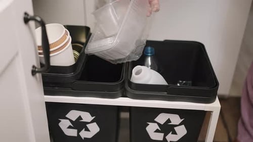 Person Places Trash Items into Recycling Container