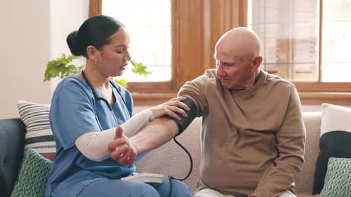 Healthcare Worker Takes Blood Pressure of Senior Adult Man