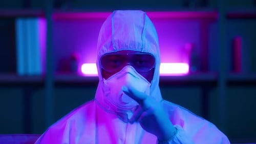 Person in Hazmat Suit Touching Mask and Goggles