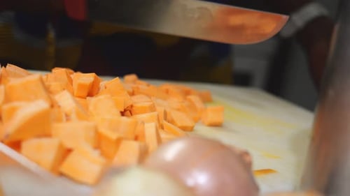 Woman chef cutting yam into concasse cubes for traditional recipe in slow motion