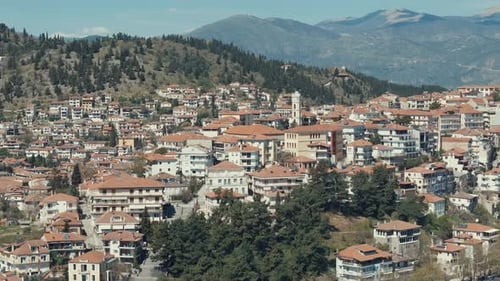 Drone orbit shot, above a village on a green hill in Europe, red roof tops, little houses, sunny wea