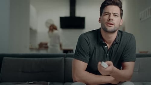 Man sitting on couch using remote control at home