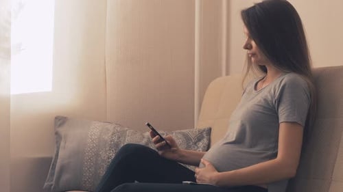 Pregnant Woman Relaxing at Home with Smartphone