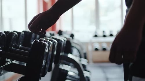 Athlete Approaches the Rack with Sports Equipment and Takes a Heavy Dumbbell Close Up Sportsman