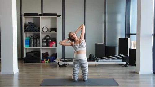 Young Woman Torso Twists in Fitness Studio