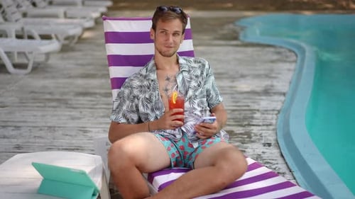 Slow Motion Smiling Man Saying Hello While Sitting on a Beach Chair on a Sunny Summer Day Outdoors