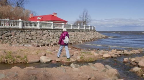 Woman Crossing Stream at Seaside Against Sky
