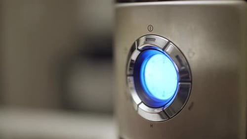 La mano de una mujer presiona el botón «Encendido» en una cafetera con pantalla LED