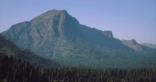Majestic Mountain Landscape Under Clear Blue Sky with Lush Forest