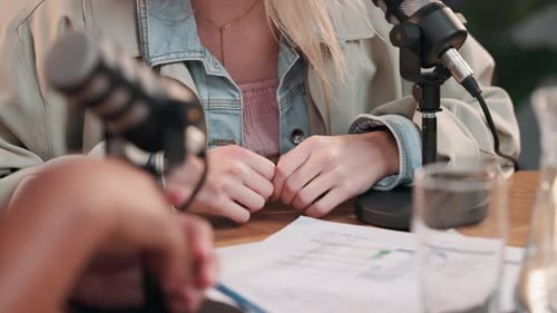 Hands, interview and podcast with guest on microphone for talk show or broadcast