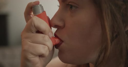 Slow Motion Close Up of a Young Woman Using an Asthma Pump