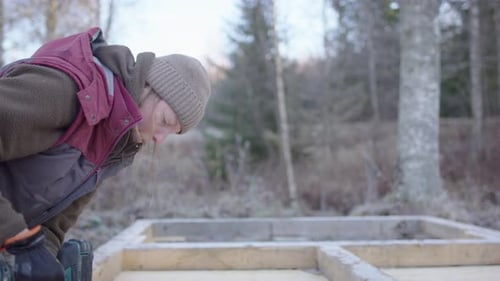 Una práctica mujer sueca usa un taladro en la estructura durante la construcción de una sauna