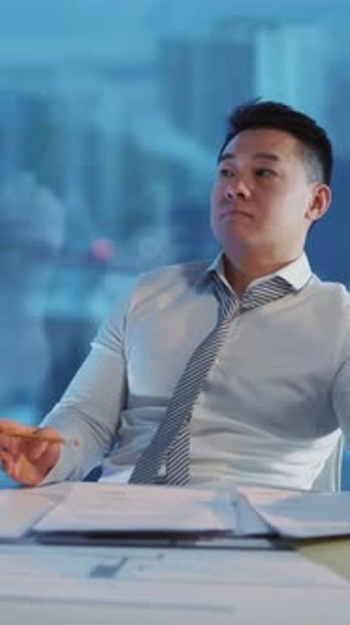 A Thoughtful Businessman is Seen in a Modern Office Setting Engaged in Deep Analysis and Planning