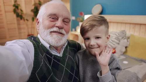 Grandfather and Grandson Smiling and Waving Indoors