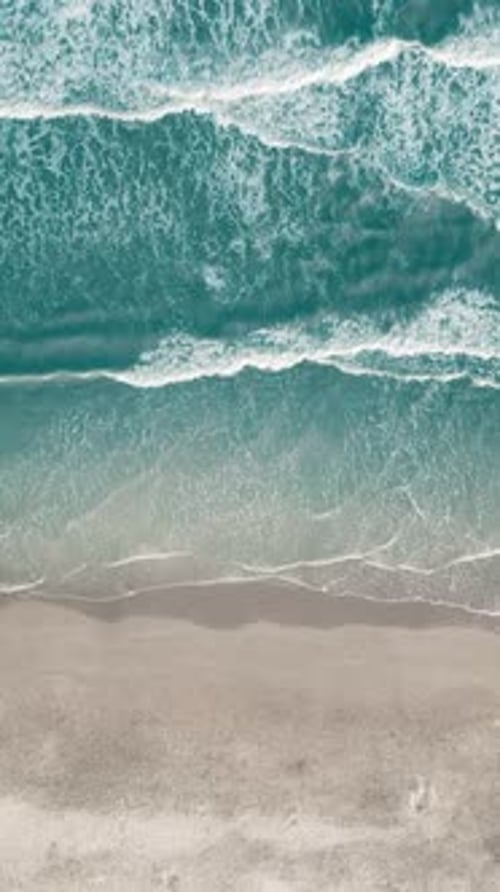 Vertical video of Drone aerial view of paradise beach. Turquoise sea water and clear sand at sunset.