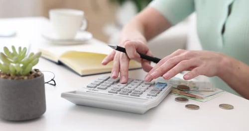 Woman Calculates Finances at Desk with Calculator and Notepad