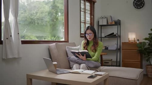 Woman wears green sweater working studying and liniving at home.